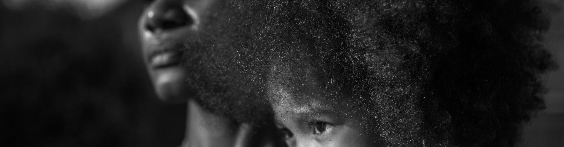 Black woman holding her daughter with an afro.
