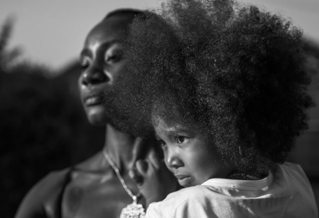 Black woman holding her daughter with an afro.