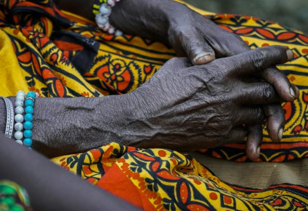 Hands of elderly black woman on african fabric